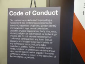 black sign with white letters detailing conference code of conduct