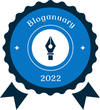 Bloganuary 2022 badge.  The tip of a fountain pen is pointing up in the center of scalloped ribbon.